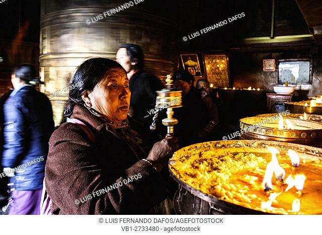 Old Tibetan woman swinging prayer wheels at Mani Lhakhang chapel, Lhasa, Tibet