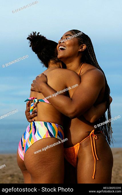 Happy woman embracing friend at beach