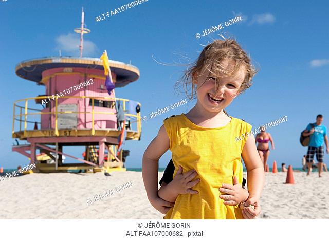 Little girl at the beach with younger brother hiding behind her