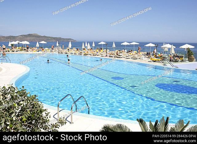 13 May 2022, Greece, Chania: Tourists enjoy the swimming pool of Panorama Hotel in Agia Marina, near the city of Chania on the island of Crete