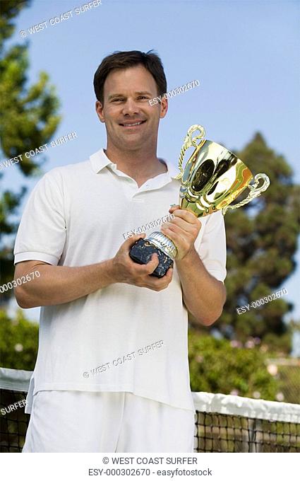 Man Holding Tennis Trophy net on tennis court portrait