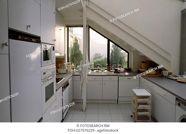 Compact modern white attic kitchen with view of roof garden through window