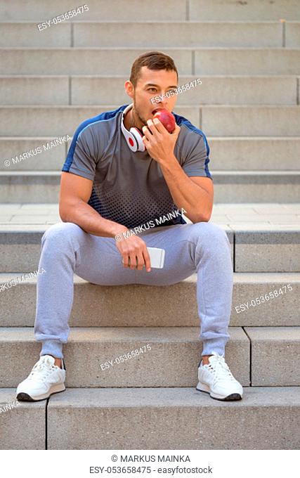 Eating apple fruit runner young man portrait format sports training fitness outdoor
