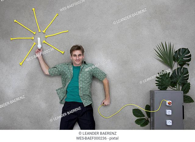 Mid adult man holding lighbulb and wire connected to socket