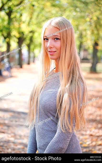 portrait of teenage girl with long blond hair enjoying sunny day outdoors
