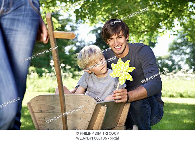 Germany, Cologne, Father and son with paper windmill, smiling