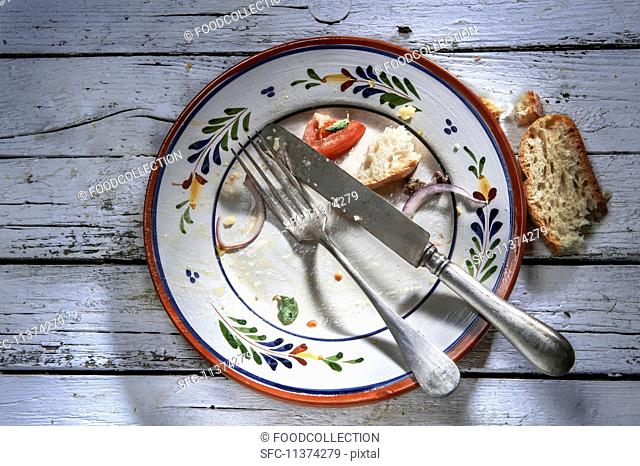 The remains of food and bread on an empty plate