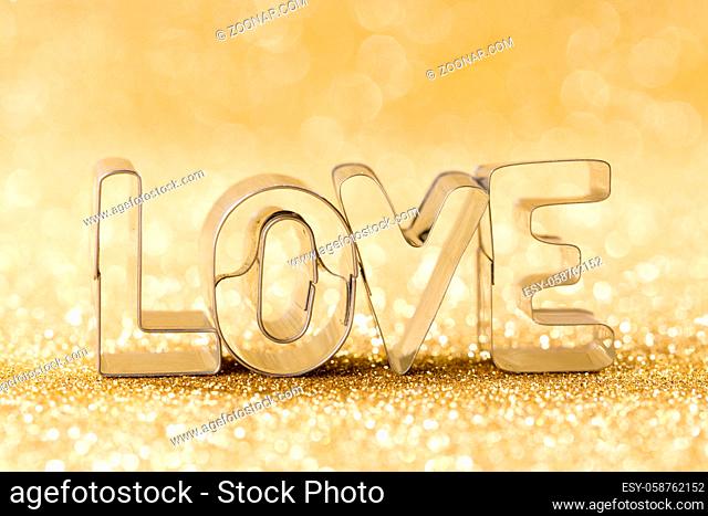 Word LOVE on golden bright glitter lights bokeh background