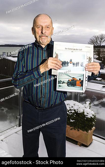 10 February 2021, Schleswig-Holstein, Eckernförde: Ulrich Cramer is standing on his terrace holding photos and a newspaper article in his hands