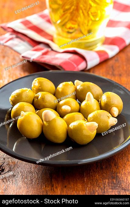 Pitted green olives stuffed with almonds on plate on wooden table