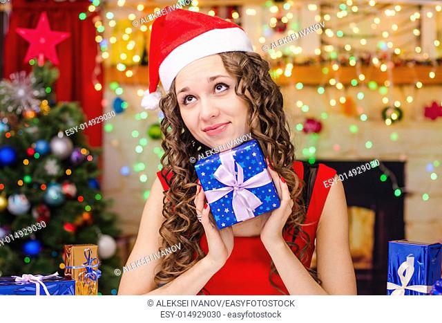 Young beautiful girl sitting at a table with Christmas gifts in the Christmas atmosphere