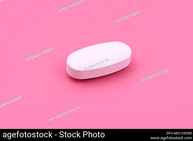 White Pharmaceutical medicine tablet on pink background, Top view. Flat lay. Copy space. Medicine concepts. Minimalistic abstract concept
