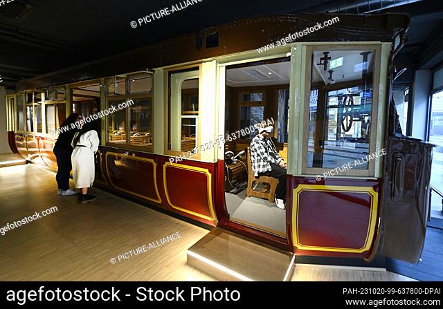 20 October 2023, North Rhine-Westphalia, Wuppertal: A man informs himself virtually sitting in the original of the wagon 11 of the series 1900 in the premises...