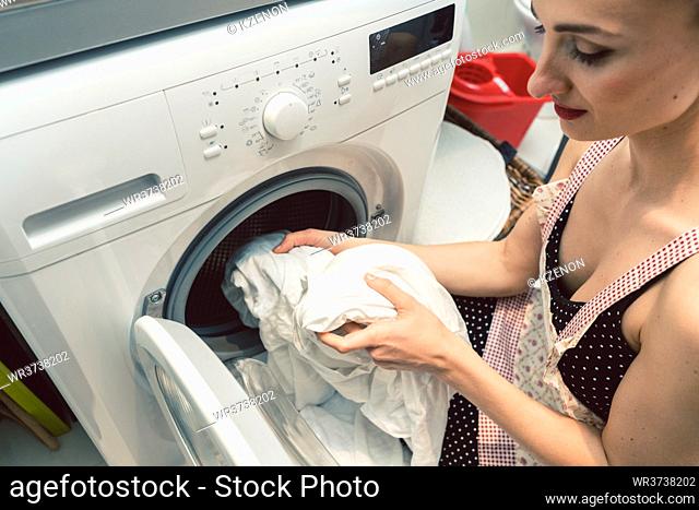 Woman homemaker operating the washing machine dialing a wheel