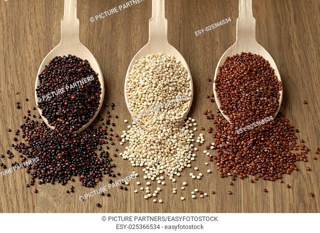 Wooden spoons with raw red, white and black quinoa