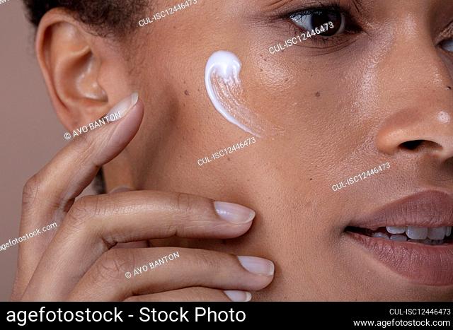 Close-up of woman applying moisturizer on face