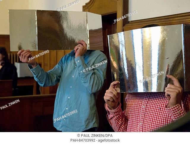 The two men Hamza Z. (R) and Aladin ö. (L) who are accused of robbing the department store KaDeWe hold up pieces of carton to cover their faces at the start of...