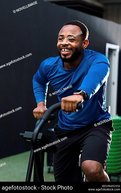 Smiling athlete exercising on airbike in gym