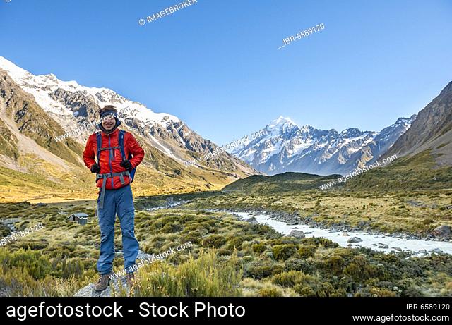 Hiker standing on a rock, Hooker Valley overlooking snow-capped Mount Cook, Hooker River, snow-capped Mount Cook National Park, Southern Alps, Canterbury