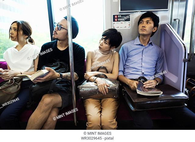 Four people sitting sidy by side on a subway train, Tokyo commuters