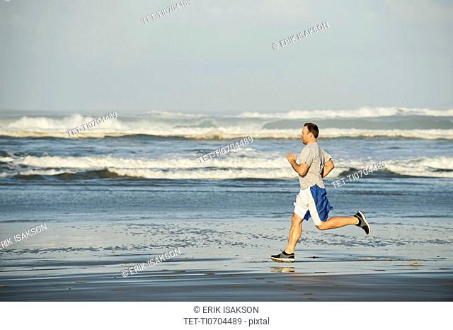 Mid adult man running on beach