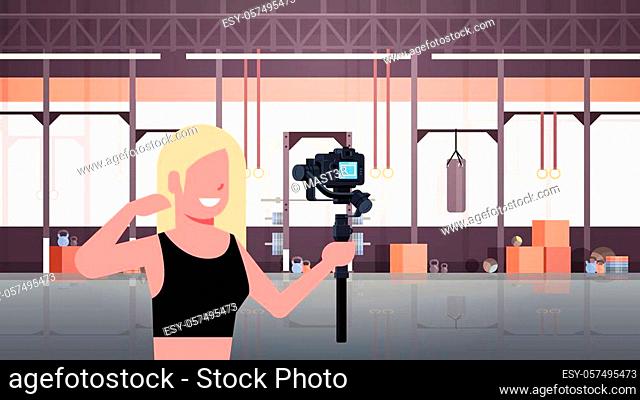 woman athlete fitness blogger shooting selfie video girl in front of DSRL camera recording herself using motorized gimbal stabilizer social media concept modern...