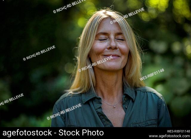 Smiling mature woman with eyes closed in garden