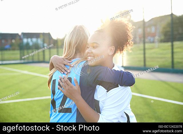 UK, Smiling female soccer team members embracing in field