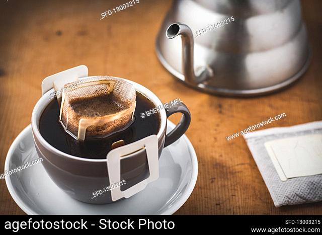 Ready brewed coffee with a coffee drip bag in a coffee cup