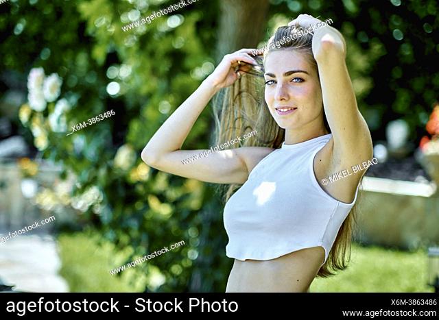 Portrait of a young beautiful caucasian woman in her 20's with long hair and blue eyes outdoor in a garden. Lifestyle concept