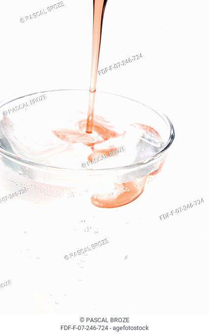 Close-up of grenadine syrup being poured into a glass of purified water