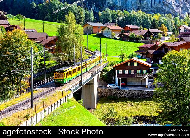 Lauterbrunnen, Switzerland - October 10, 2019: Alpine wooden houses and Wengernalpbahn train, Swiss Alps, Jungfrau region