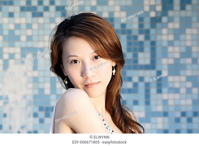 Here is a beautiful Asian lady in front of mosaic and looking