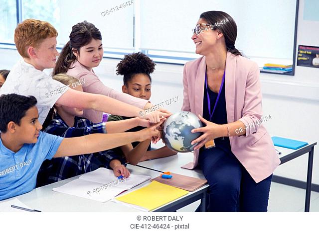 Eager students touching globe in geography teachers hands