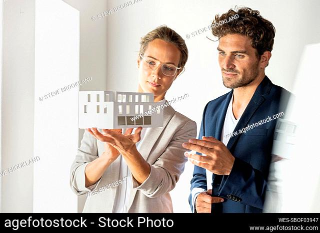 Businesswoman with house model standing by colleague at office