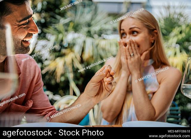 Happy man surprising woman with ring