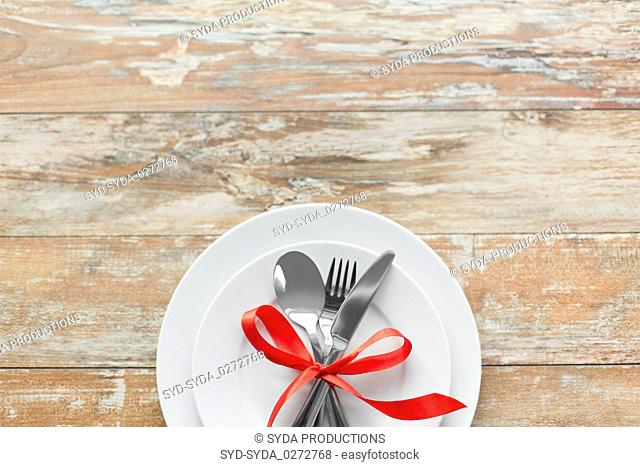 cutlery tied with red ribbon on set of plates