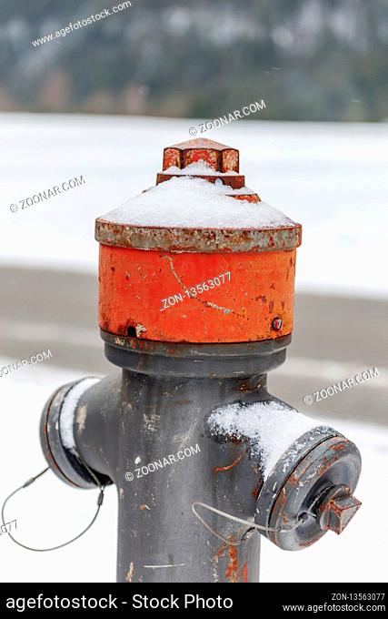 Upper part of an old rusty overhead hydrant on a side street in Bavaria in snowy winter. Oberer Teil eines alten rostigen Oberflur-Hydranten an einer...