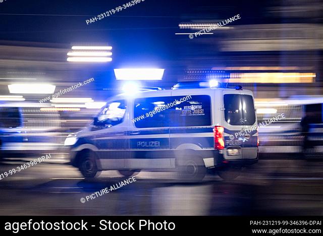 18 December 2023, Saxony, Dresden: A police car with flashing blue lights drives across the Augustus Bridge at the edge of a demonstration of the right-wing...