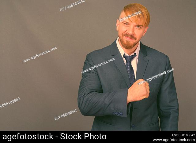 Studio shot of bearded businessman with blond hair against gray background