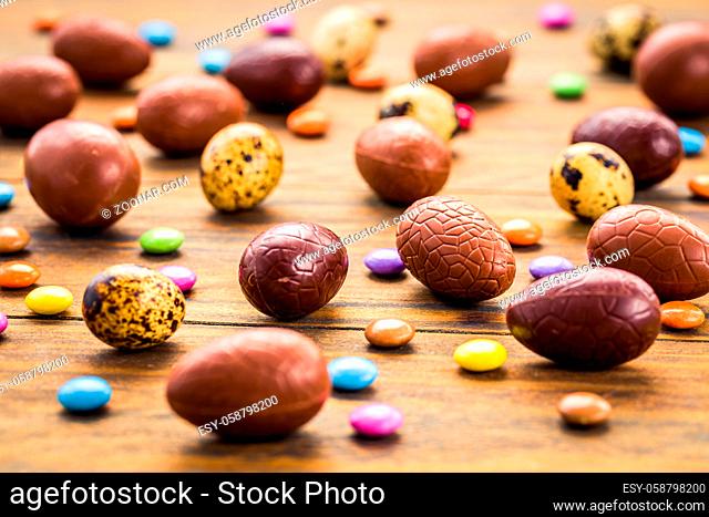 Sweet chocolate eggs and colorful sweets for Easter on wooden background