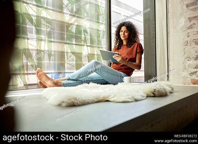 Smiling female professional using digital tablet while sitting by window
