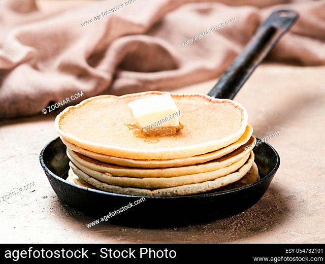homemade pancakes with butter in iron cast. Stack of pancakes on brown concrete background. Close up