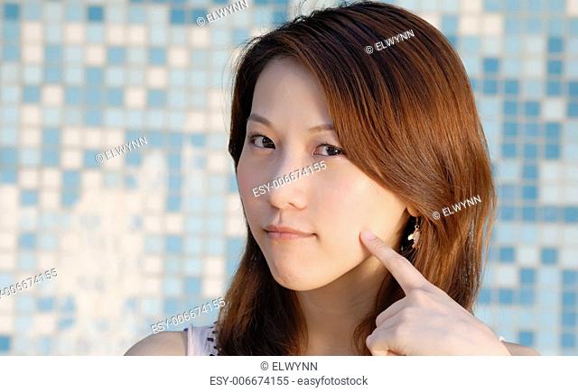 Here is a beautiful Asian lady in front of mosaic and watching