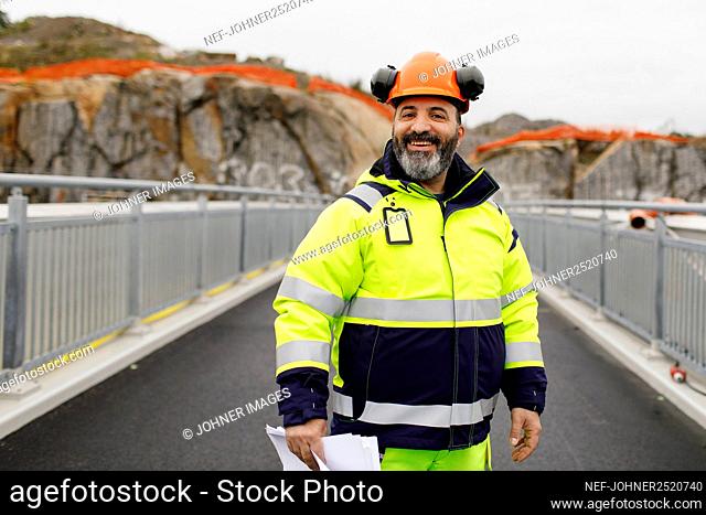 Portrait of male engineer in reflecting clothing standing on bridge