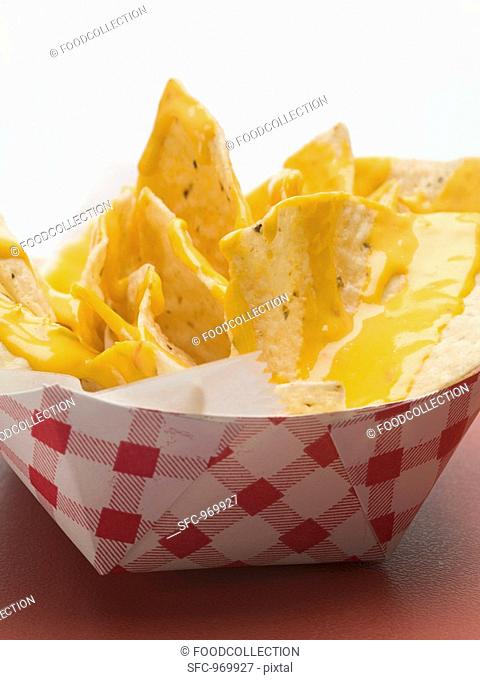 Nachos with cheese sauce in paper dish close-up