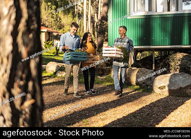 Friends carrying crates with freshly harvested organic vegetables at farm