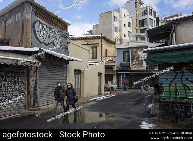 17 February 2021, Greece, Athen: A man and a woman walk past closed shops in the Monastiraki district of Athens. A strict lockdown has been in effect for the...