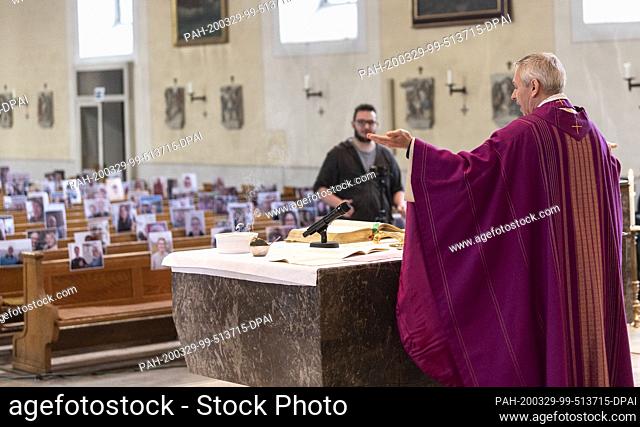 29 March 2020, Baden-Wuerttemberg, Achern: Priest Joachim Giesler stands in front of photos with parishioners in the parish church