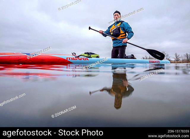 Fort Collins, CO, USA - March 14, 2020: A senior male paddler on a long racing stand up paddleboard (Mistral Stealth). Low angle view from action camera on a...